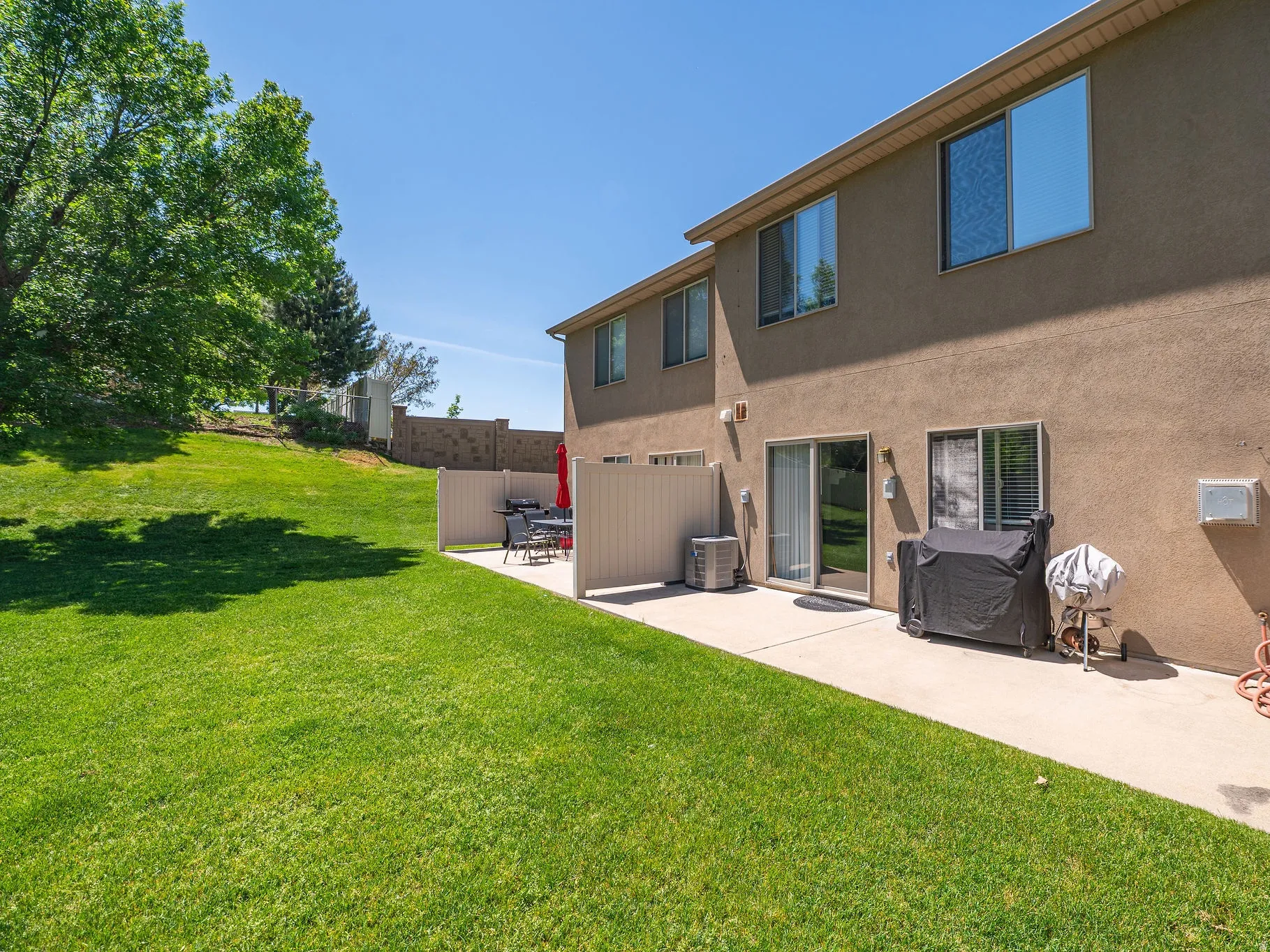 Expansive grassy yard with a sloping landscape
