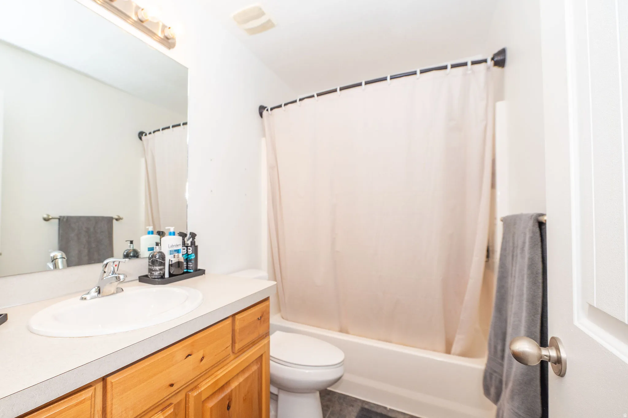 Bathroom featuring a single vanity with wood-finish cabinetry, a neutral countertop, and an integrated sink