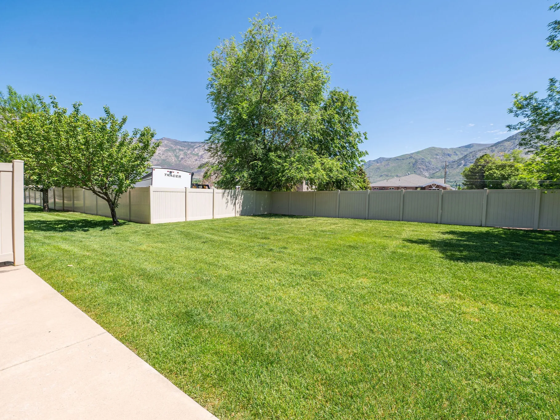 Expansive grassy yard with mature trees and a perimeter privacy fence