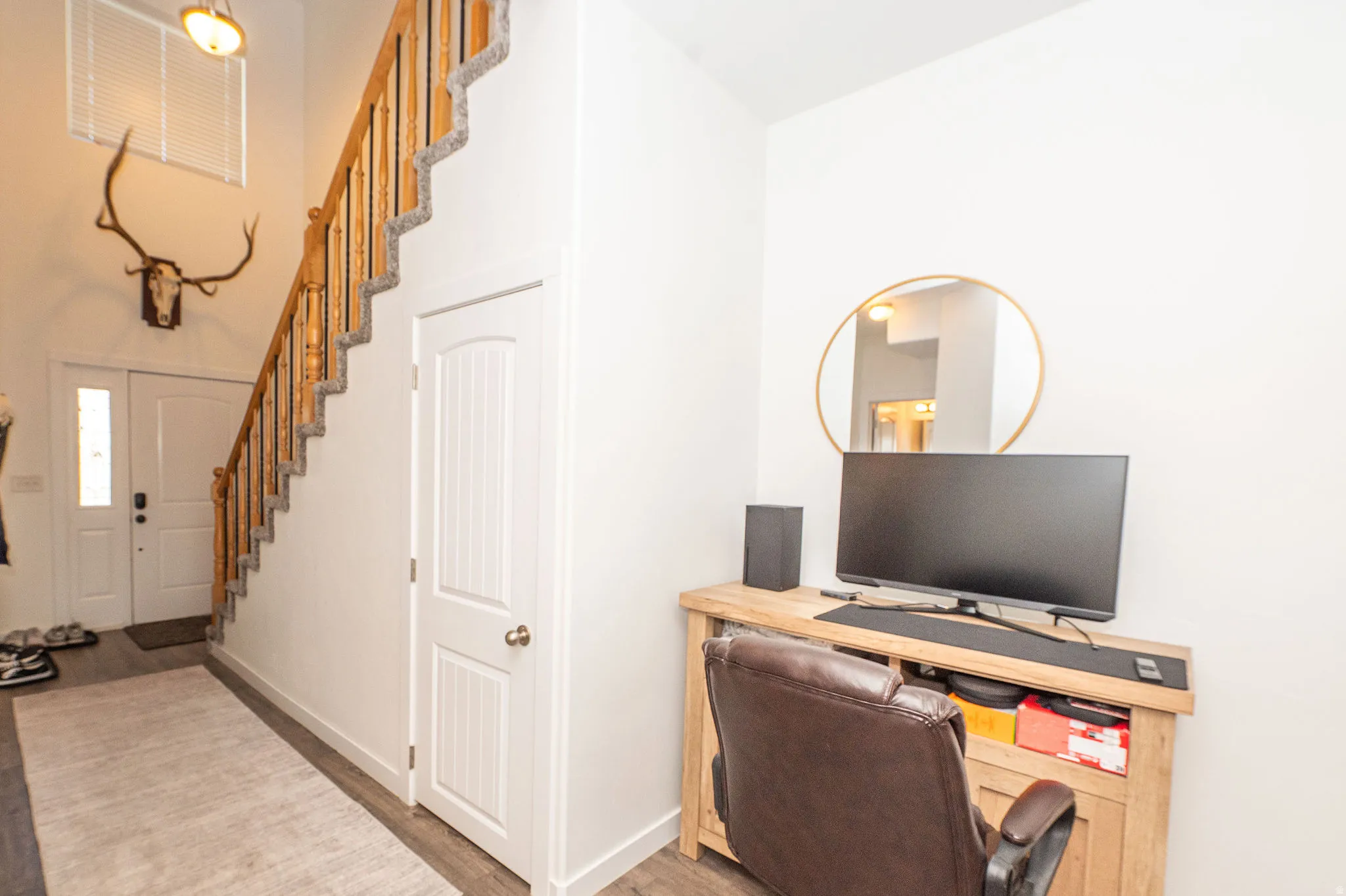 Entryway featuring wood-finish flooring and a staircase with a natural wood handrail and balusters