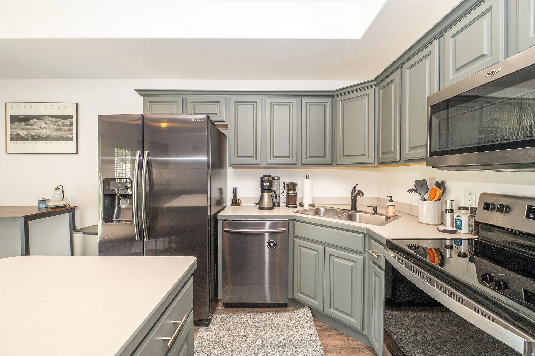 Kitchen featuring gray shaker-style cabinetry, stainless steel appliances, and light-toned countertops