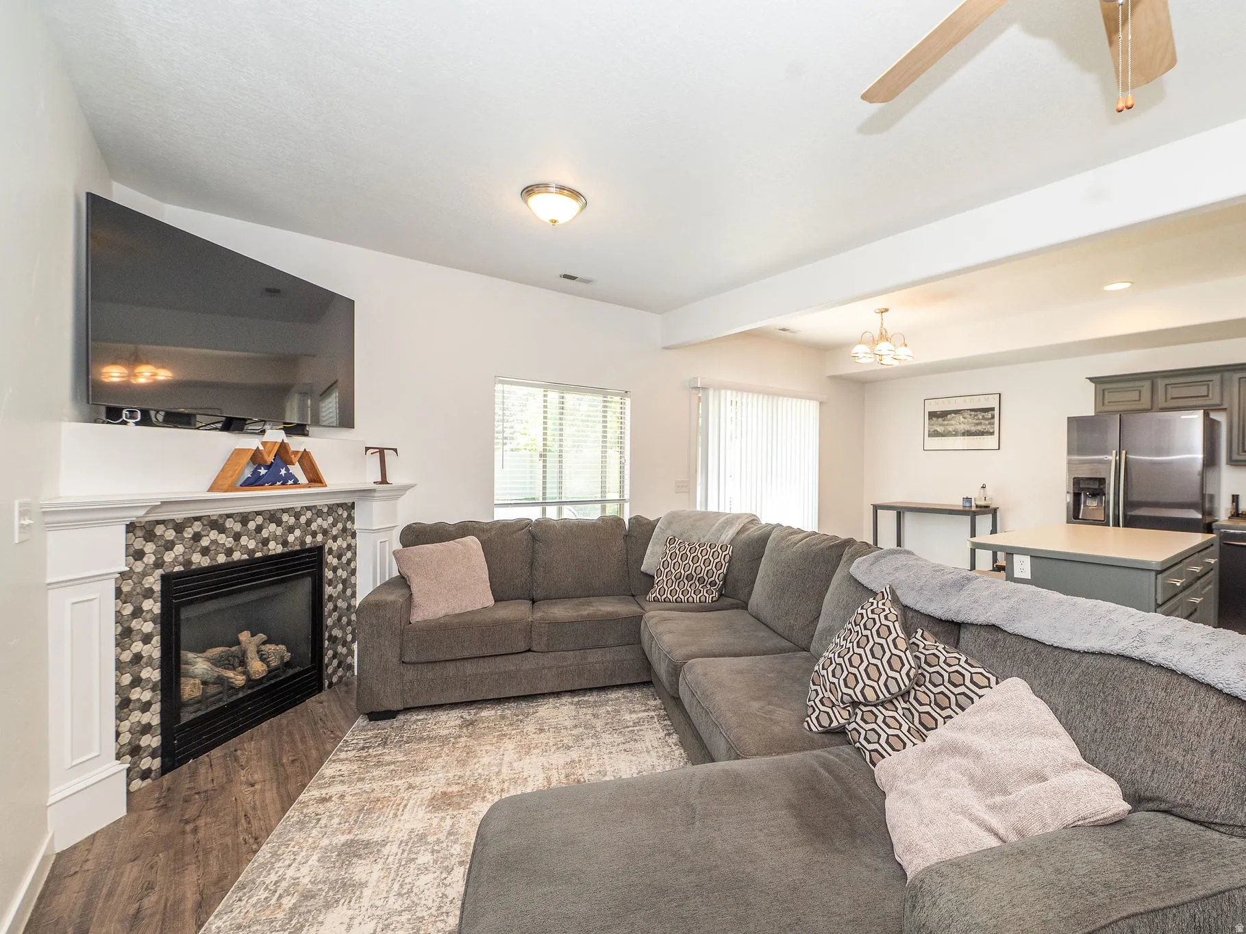 Living room featuring a tiled fireplace with a mantel, wood-finish flooring, and recessed lighting