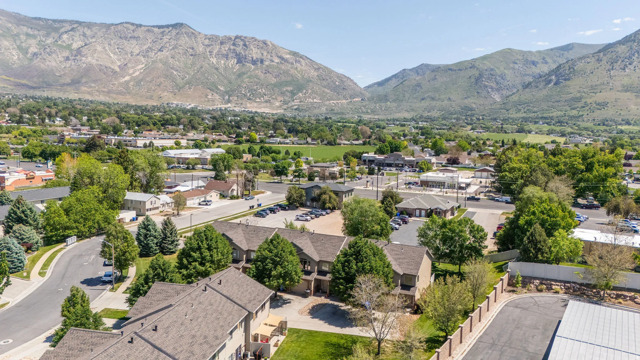Residential community with paved streets and mature trees, surrounded by mountainous terrain and a verdant valley