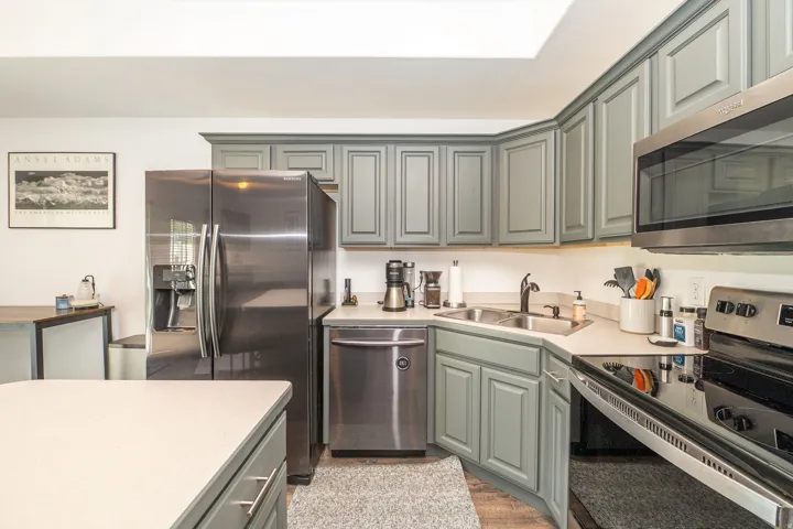 Kitchen featuring gray shaker-style cabinetry, stainless steel appliances, and light-toned countertops
