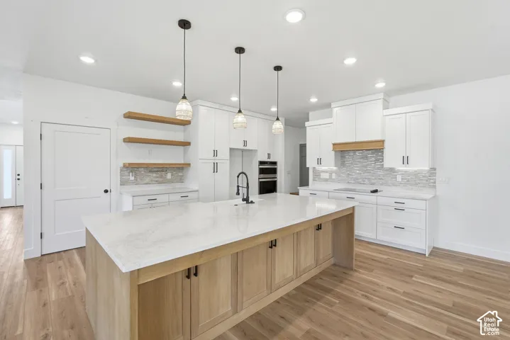 Spacious kitchen featuring an expansive center island with light wood-finish cabinetry and a light-toned countertop, complemented by white perimeter cabinetry with dark hardware
