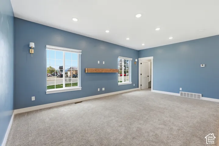 Spacious room with light blue walls and neutral carpeting