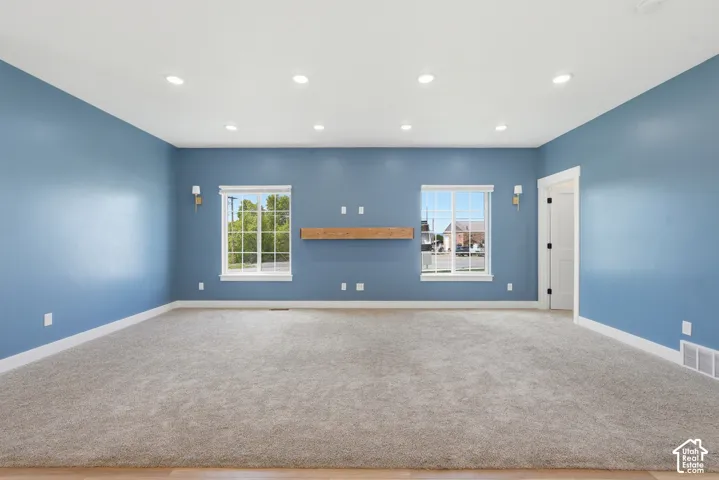 Spacious room featuring plush gray carpeting, light blue walls, and a recessed lighting system