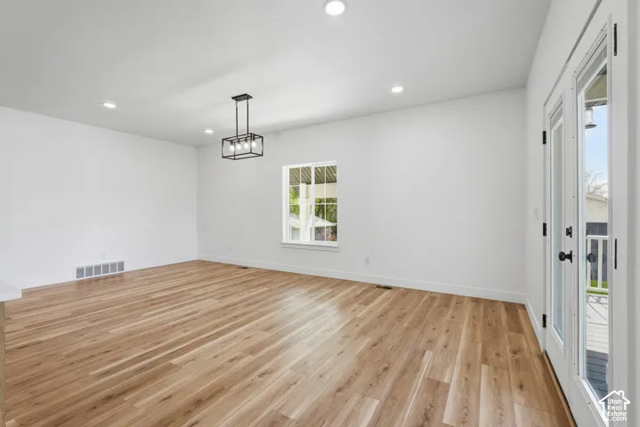 Bright interior space featuring wood-finish flooring, recessed lighting, and a contemporary black chandelier