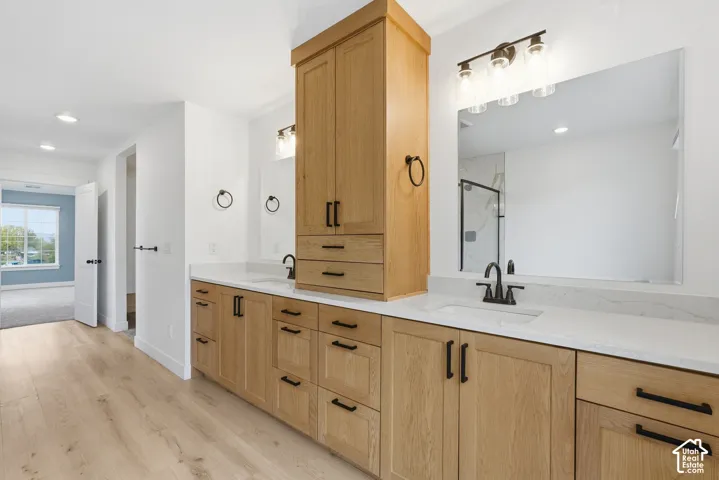 Dual vanity with light wood cabinetry, white countertops, and matte black hardware