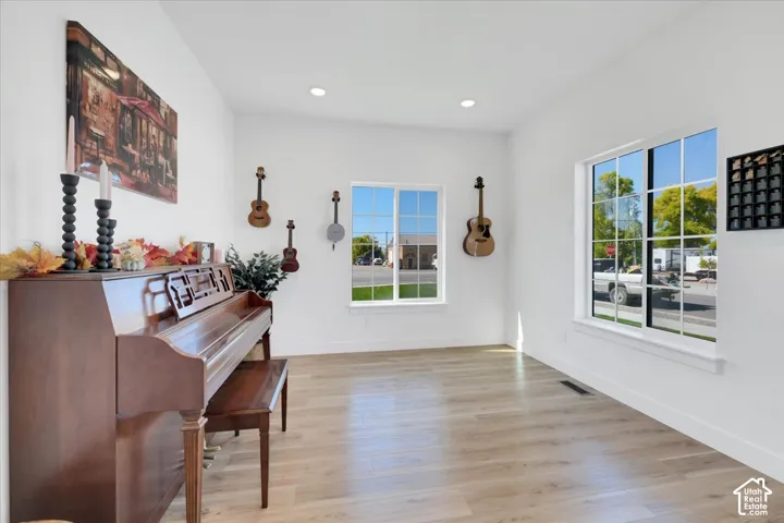 Bright room with light wood-finish flooring, white walls, and recessed lighting
