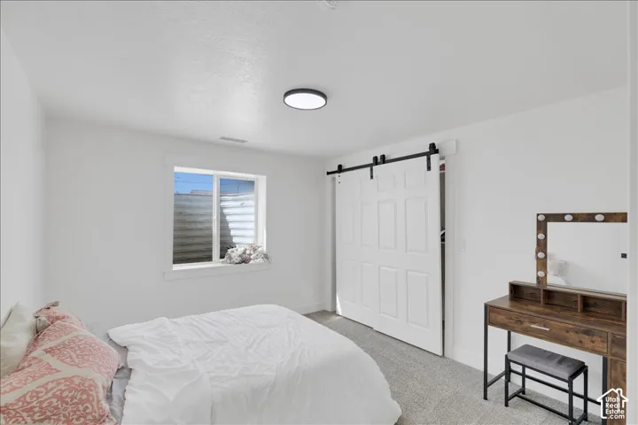 Bedroom featuring a white barn door, recessed window, and flush-mount ceiling light