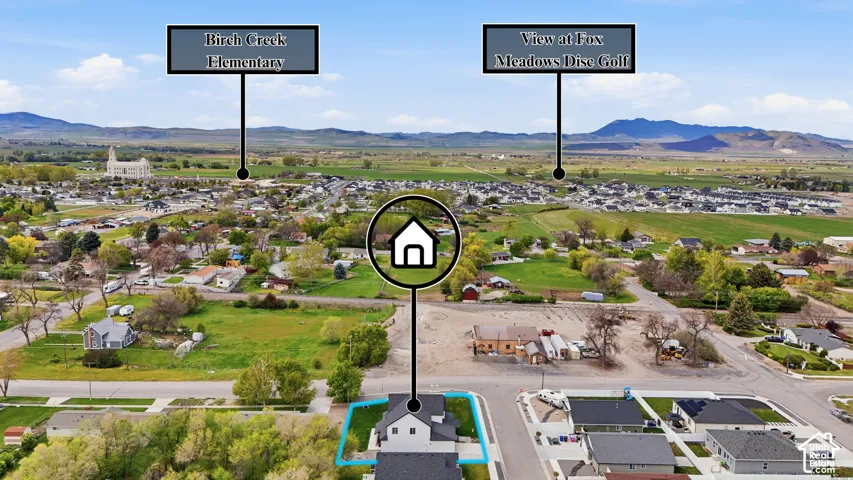 Aerial overview showcasing a property with a distinct, light-colored roof and dark trim, positioned within a developing neighborhood
