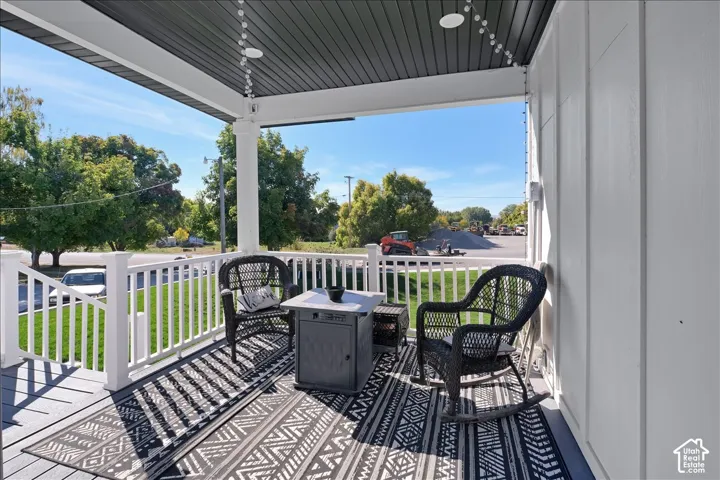 Covered front porch featuring a white railing and dark wood-finish flooring