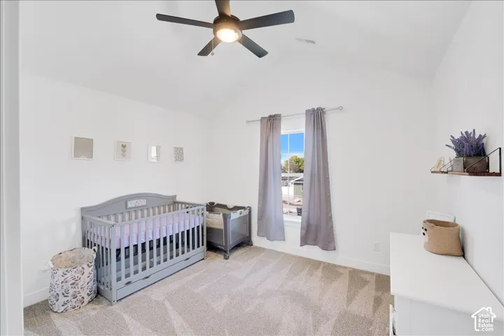 Room with vaulted ceiling, light-toned carpet, and a window with curtains