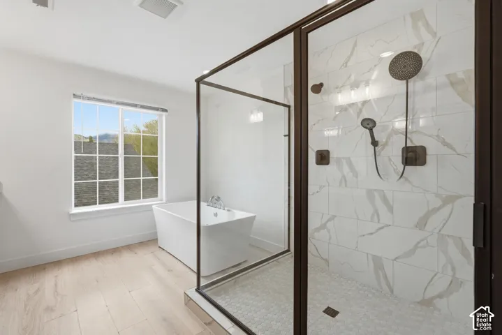 Spacious bathroom featuring a frameless glass-enclosed shower with bronze-finish fixtures, white marble-style tiled walls, and a hexagonal tiled floor