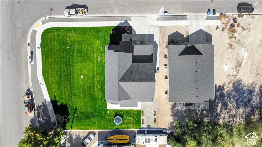 Corner lot location with a spacious side yard, asphalt shingles on the main roof, concrete driveway, and established green lawn