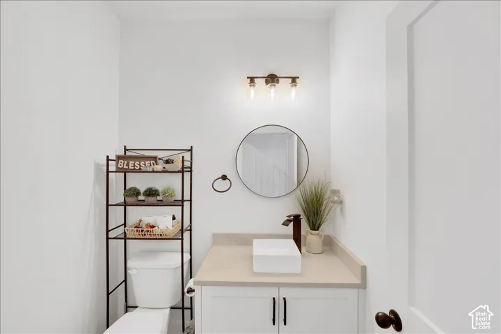 Bright white powder room featuring a contemporary vanity with a vessel sink, a bronze-finish faucet, and a round wall mirror