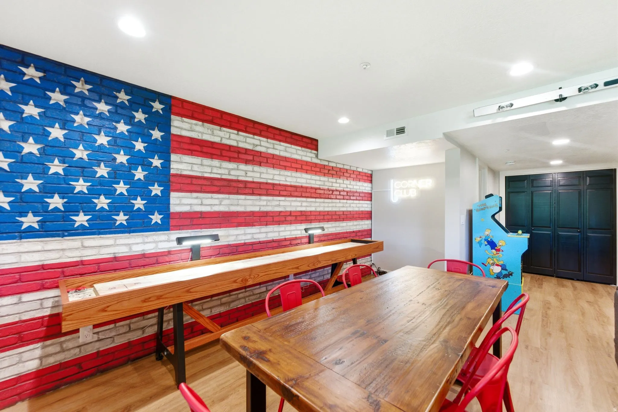 Recreation room featuring a painted brick accent wall, wood-finish flooring, recessed lighting, and a long wooden table