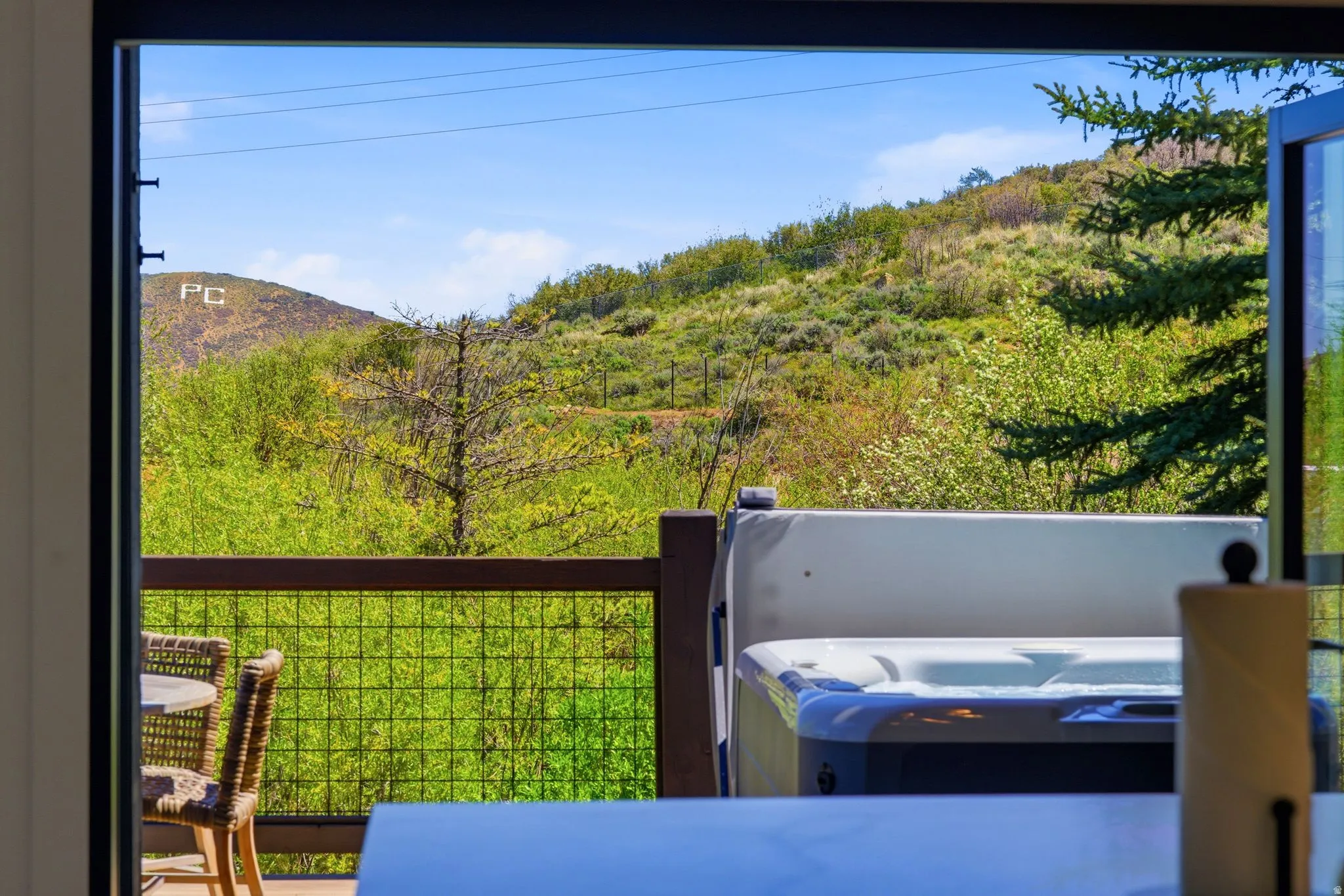 Outdoor deck featuring a built-in hot tub, dark wood railing, and metal grid infill