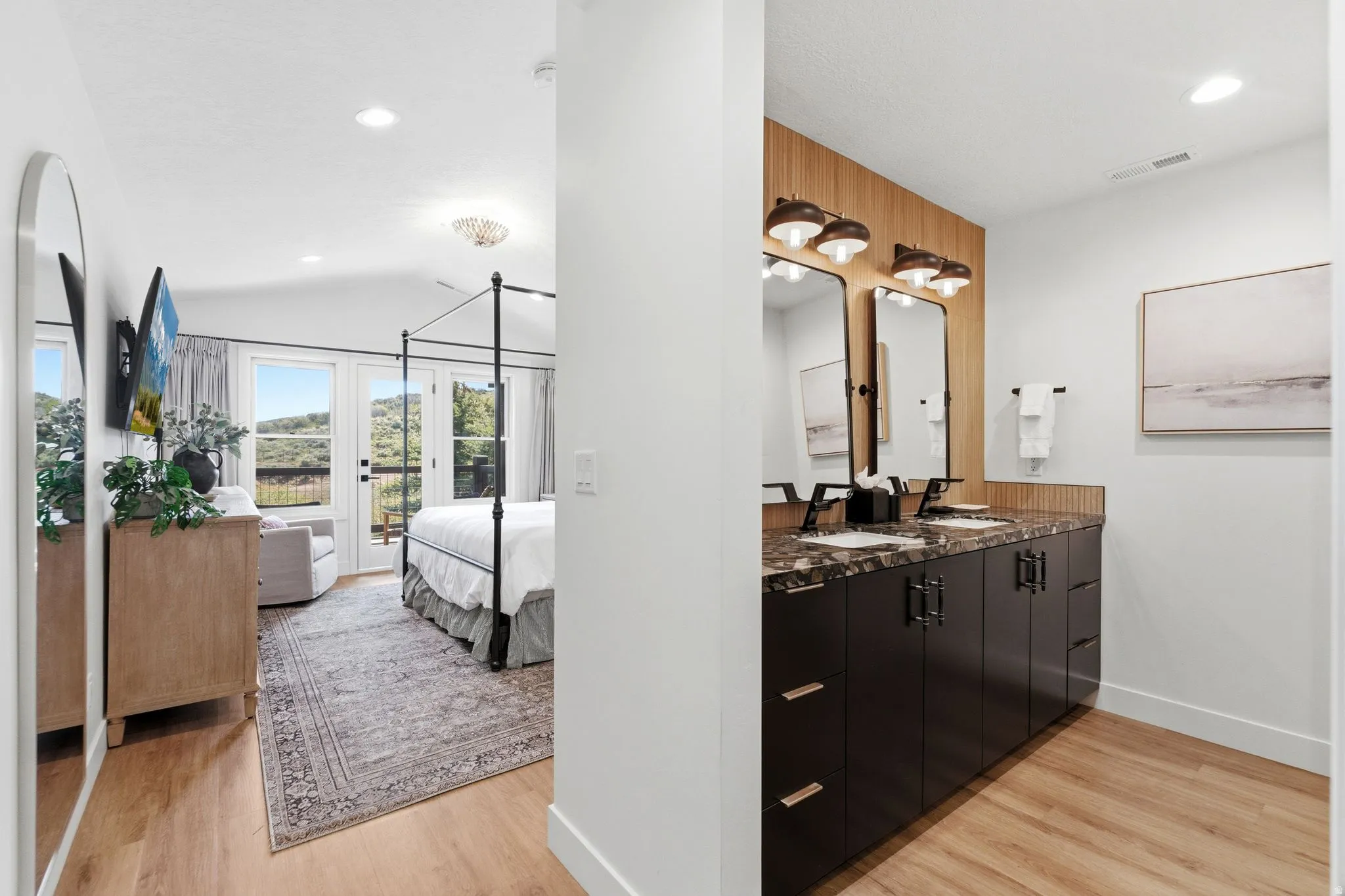 Dual vanity with dark cabinetry, stone countertop, and two framed mirrors