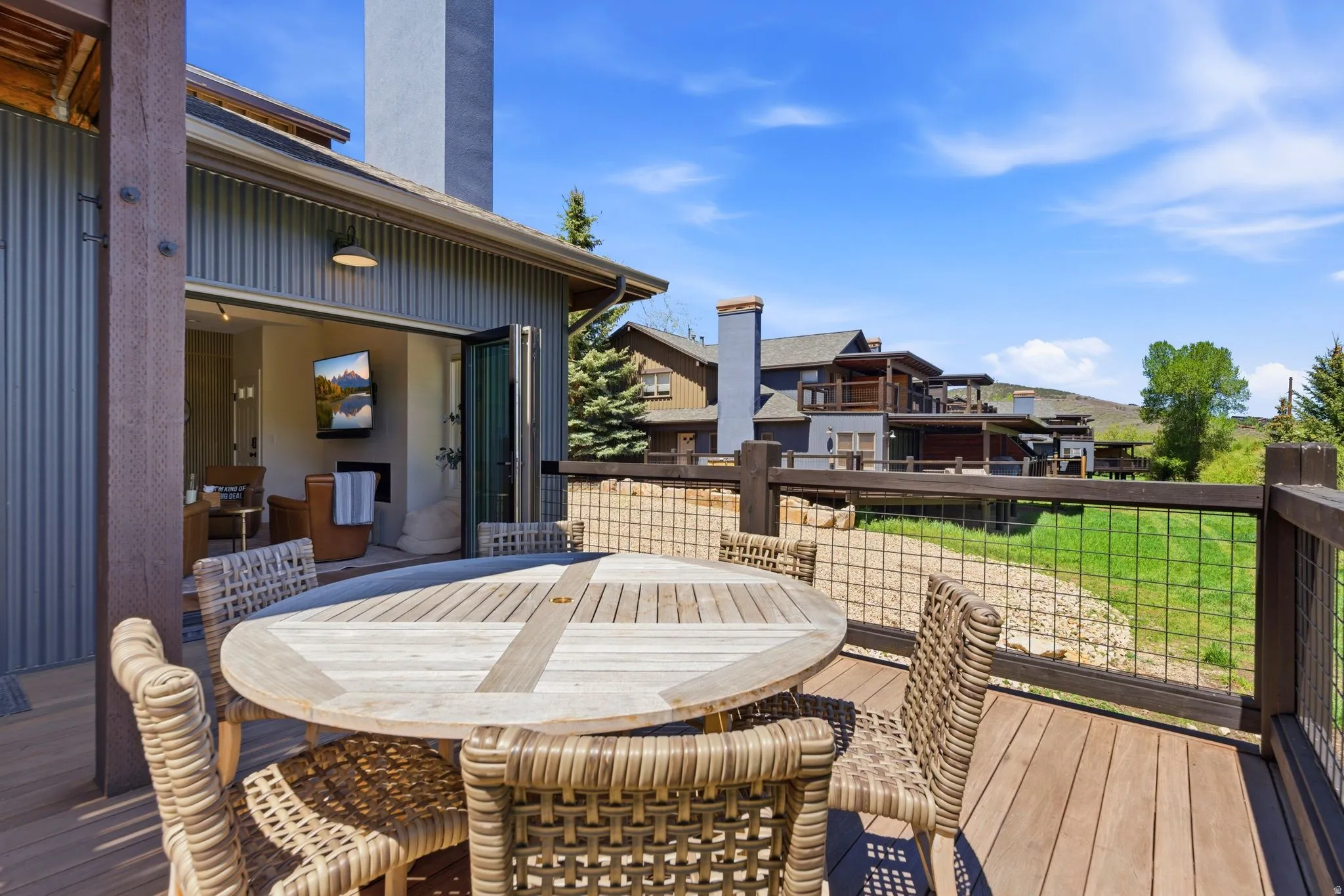 Expansive outdoor deck featuring wood-finish flooring and dark wood railings with wire mesh