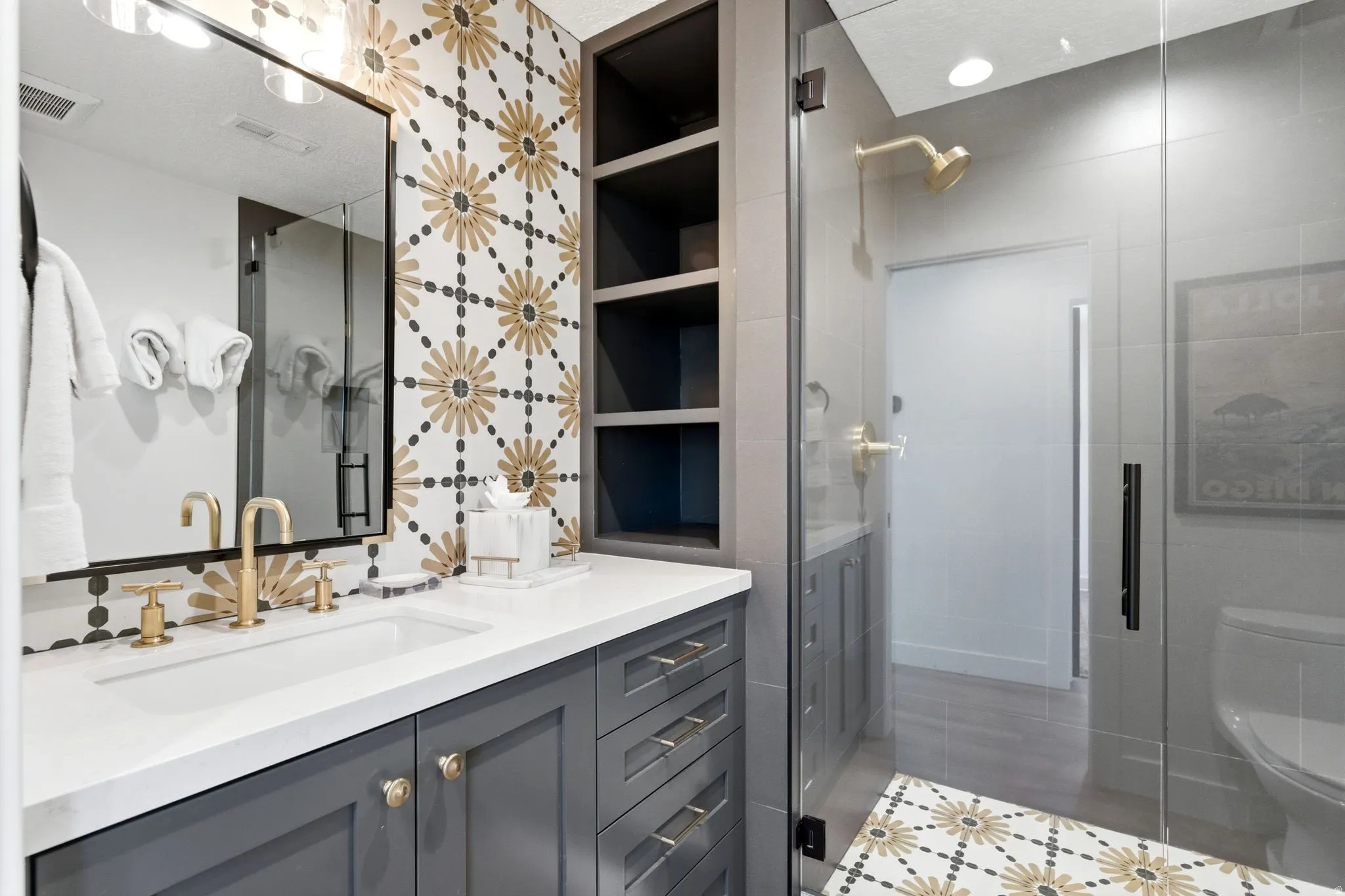 Bathroom vanity featuring a single rectangular undermount sink, brass-finish faucet, and a white countertop