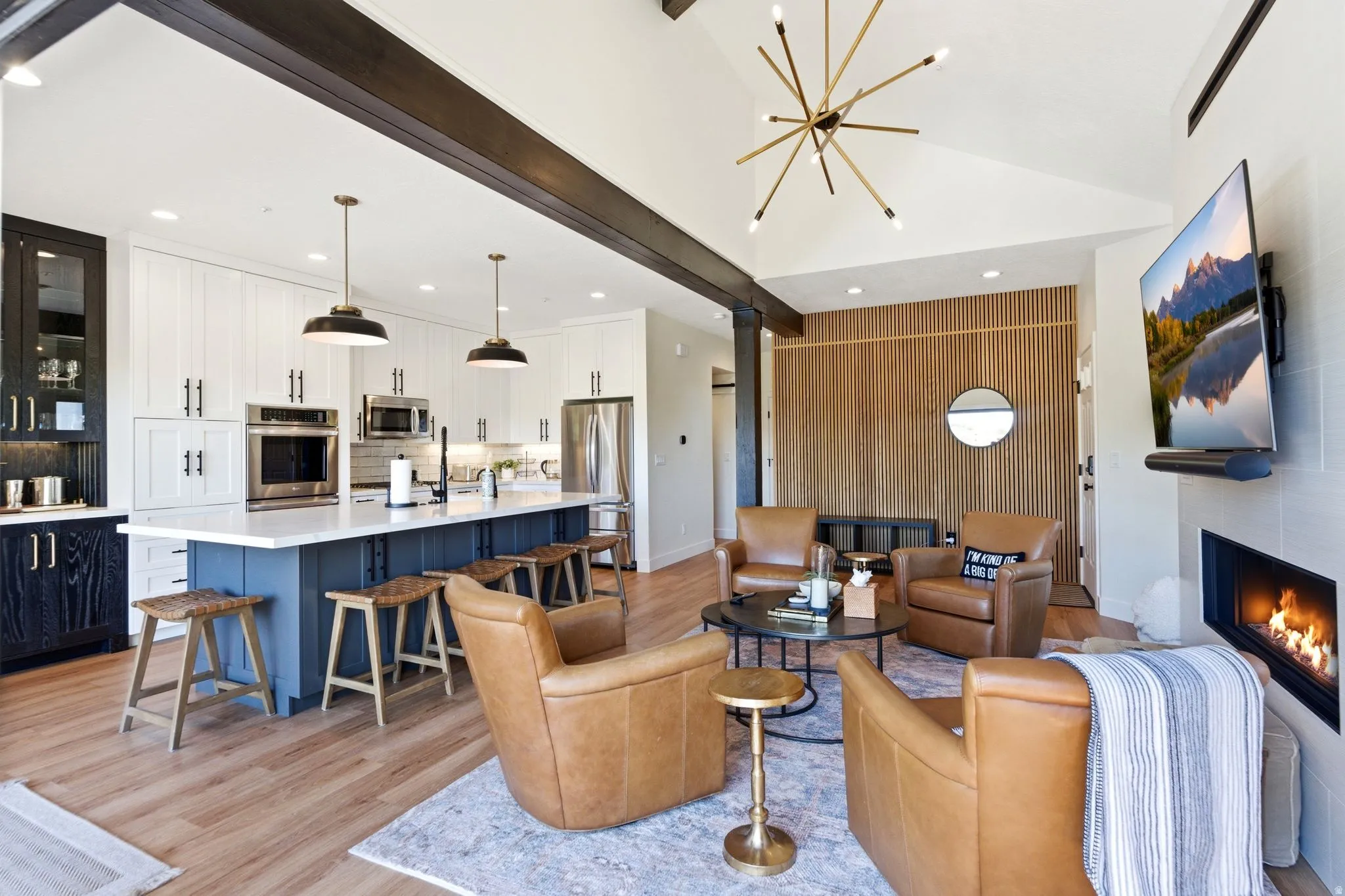 Open concept living space featuring wood-finish flooring, a vaulted ceiling, and exposed dark wood beams