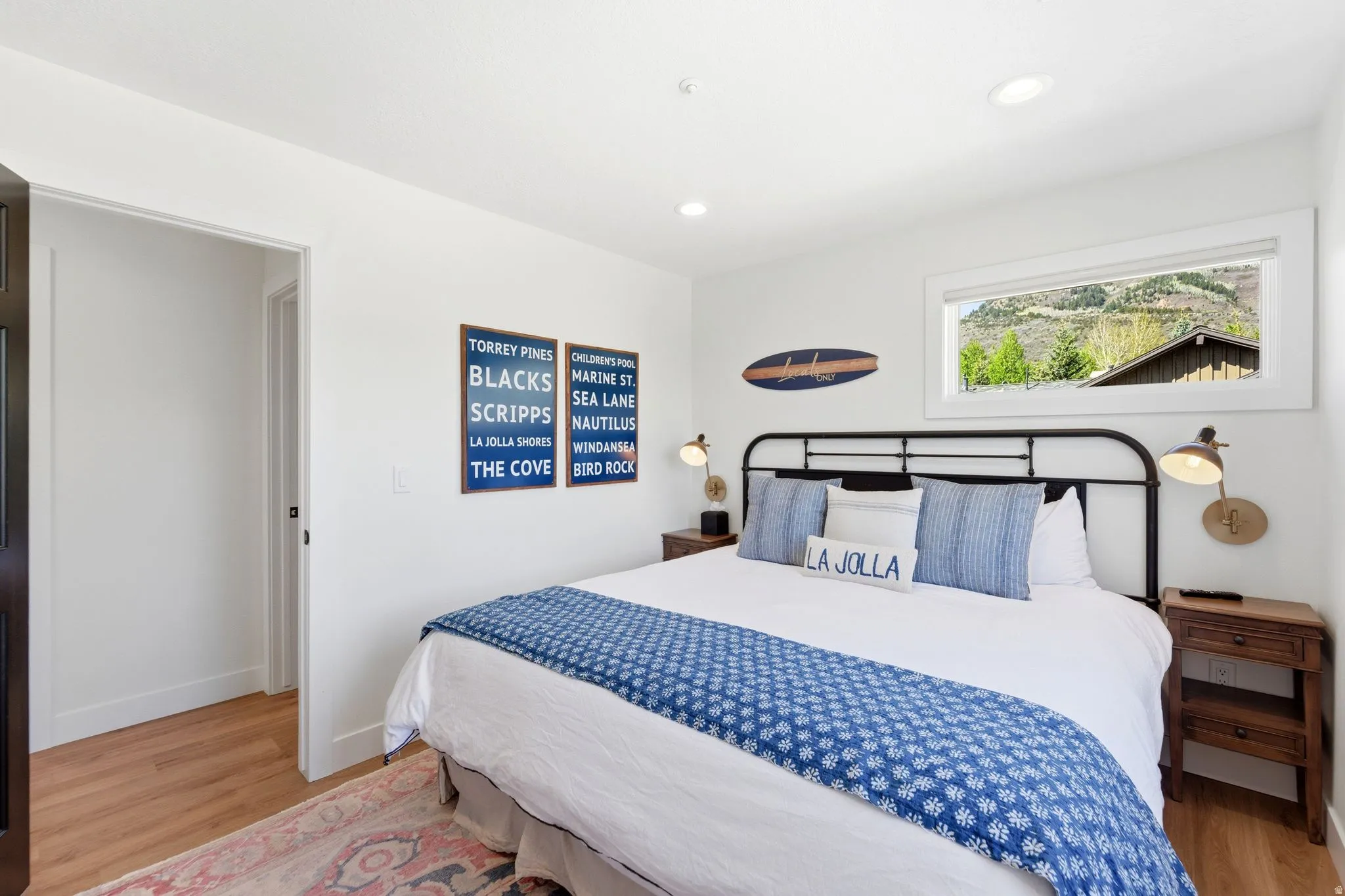 Bright bedroom featuring wood-finish flooring, recessed lighting, and a panoramic window showcasing a mountain backdrop