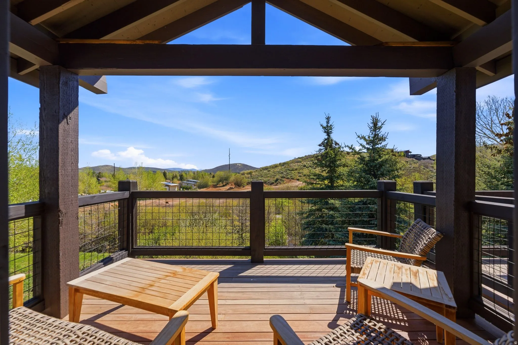 Expansive outdoor deck featuring wood-finish flooring, a sturdy wood beam ceiling, and a cable railing system