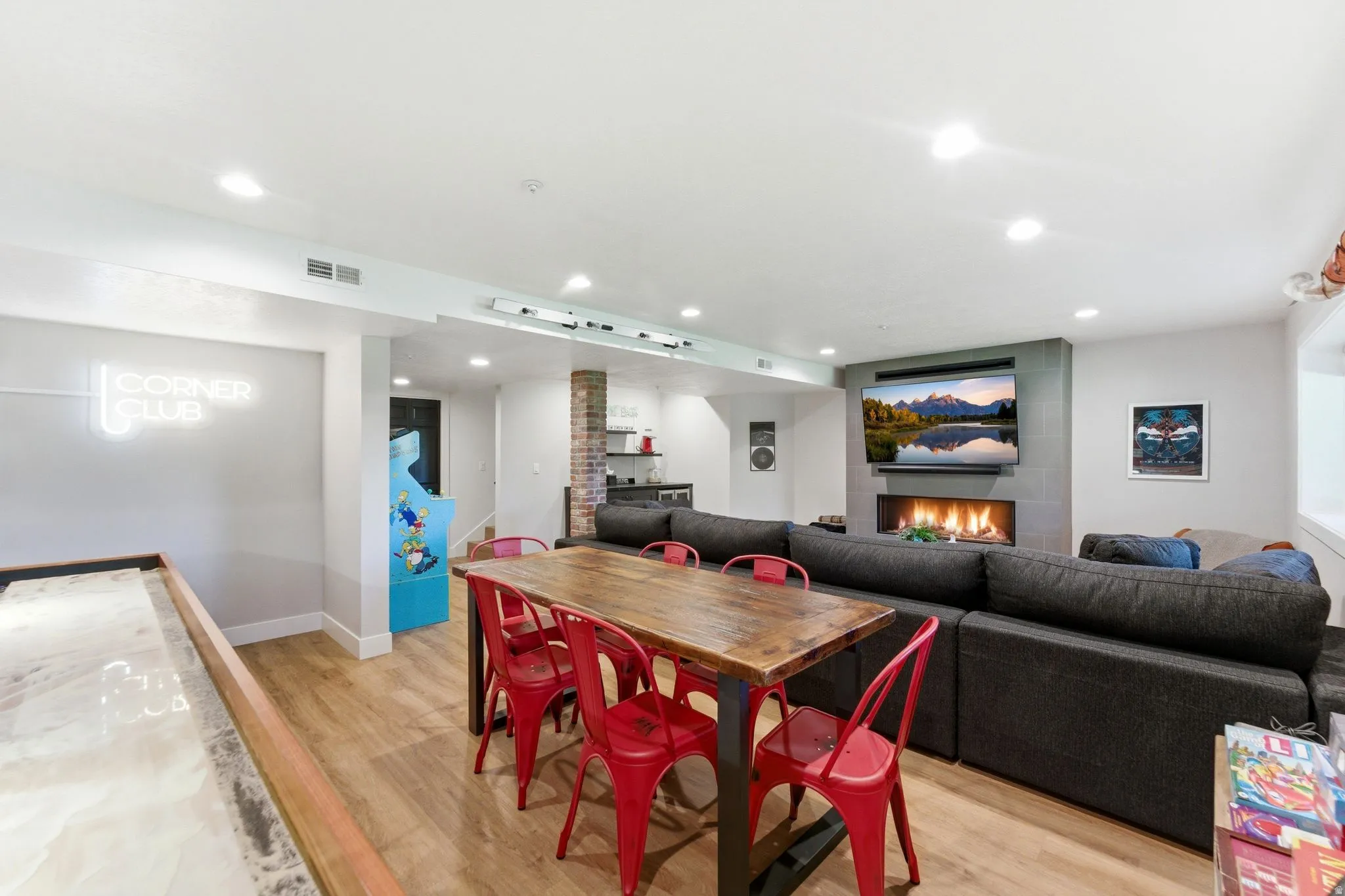 Entertainment area featuring wood-finish flooring, recessed lighting, and a linear fireplace with a tiled surround