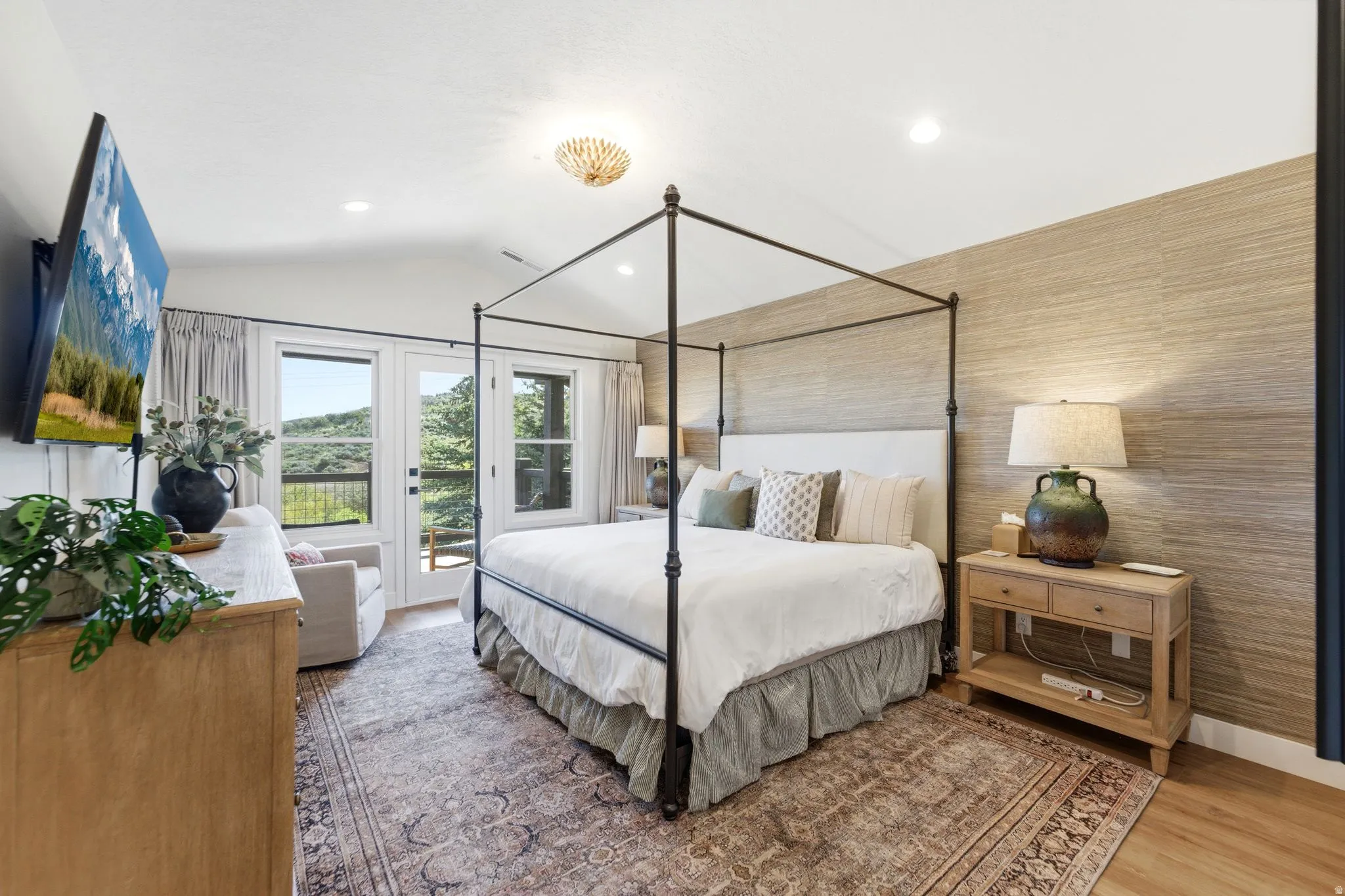 Bedroom with vaulted ceiling, wood-finish flooring, and a textured accent wall