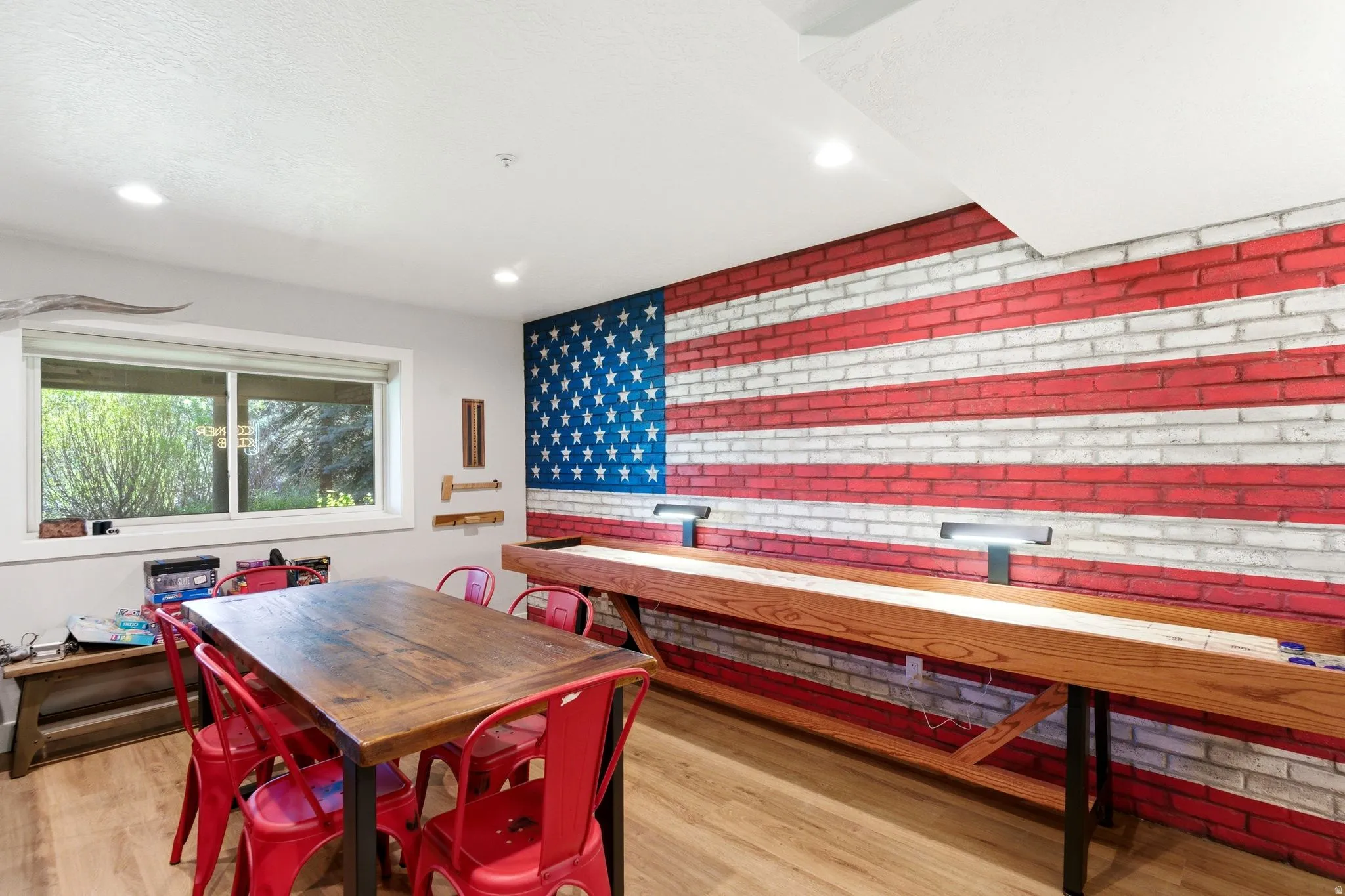 Recreation space featuring a prominent brick accent wall, recessed lighting, wood-finish flooring, and a large window