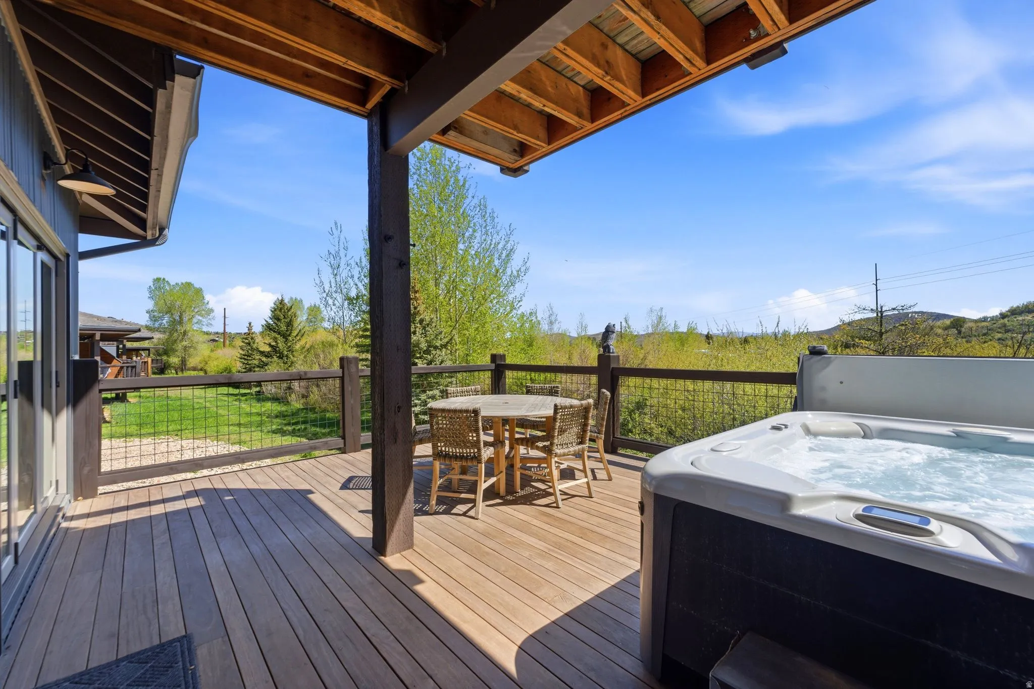 Expansive outdoor deck featuring wood-finish flooring, a built-in hot tub, and a covered dining area