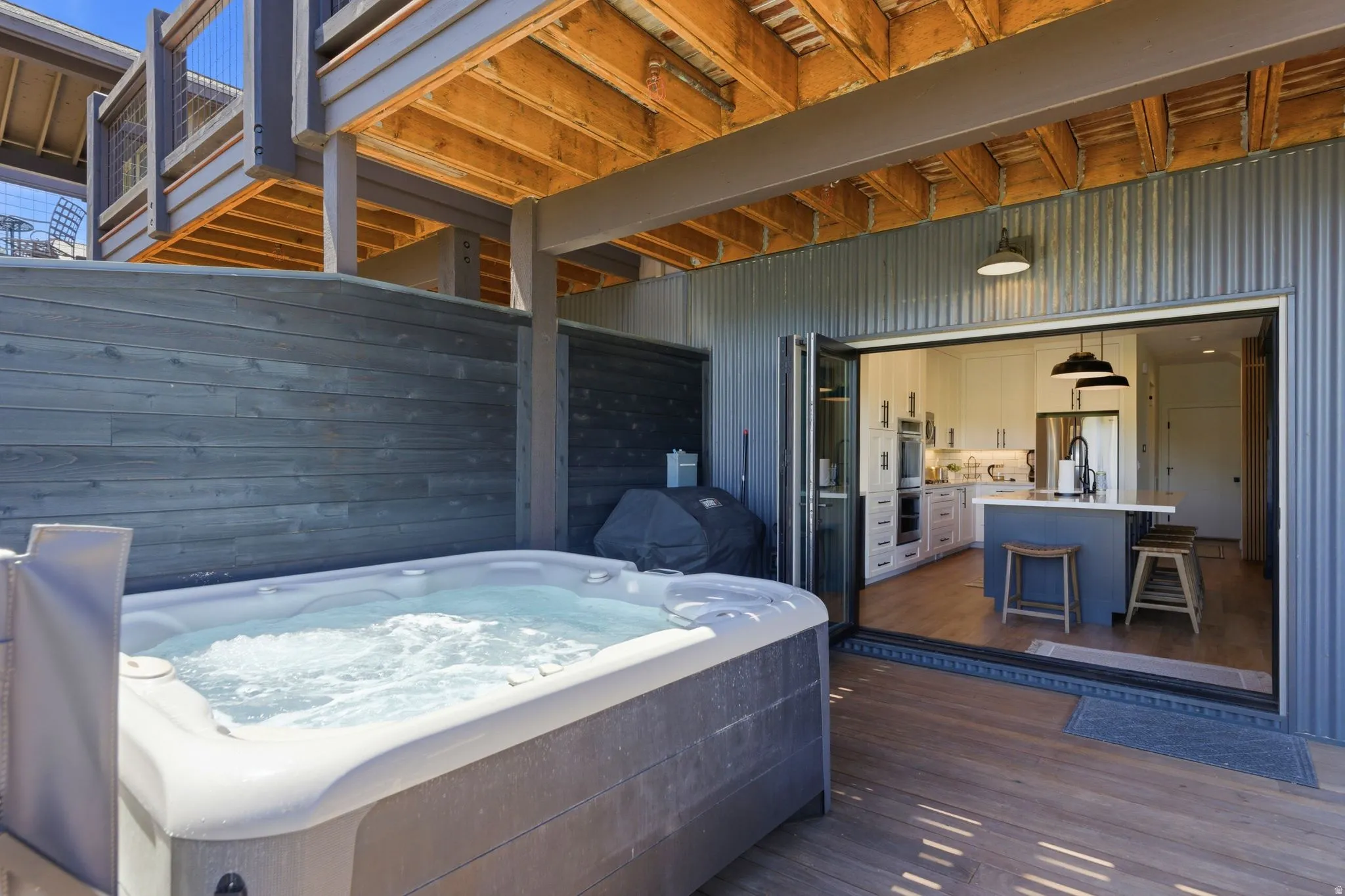 Outdoor spa area featuring a built-in spa, wood-finish decking, and grey horizontal slat fencing