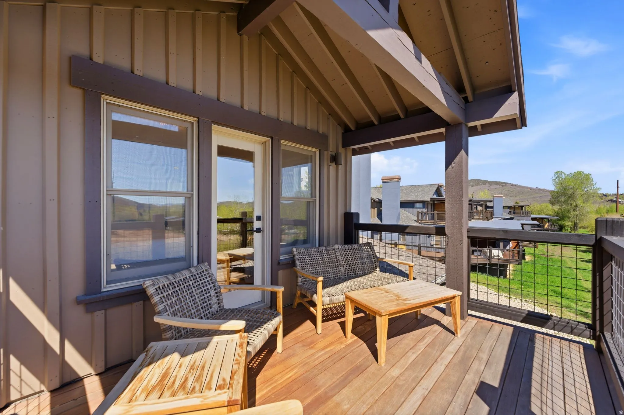Spacious outdoor balcony featuring natural wood decking and a metal grid railing
