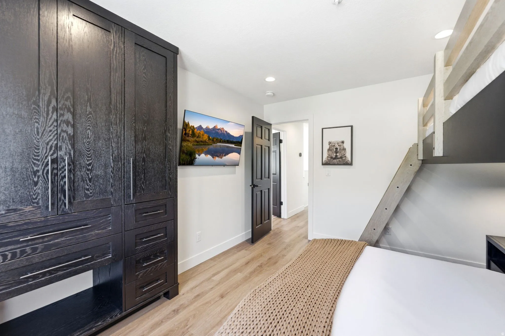Built-in dark wood cabinetry with silver hardware, light wood-finish flooring, and white walls