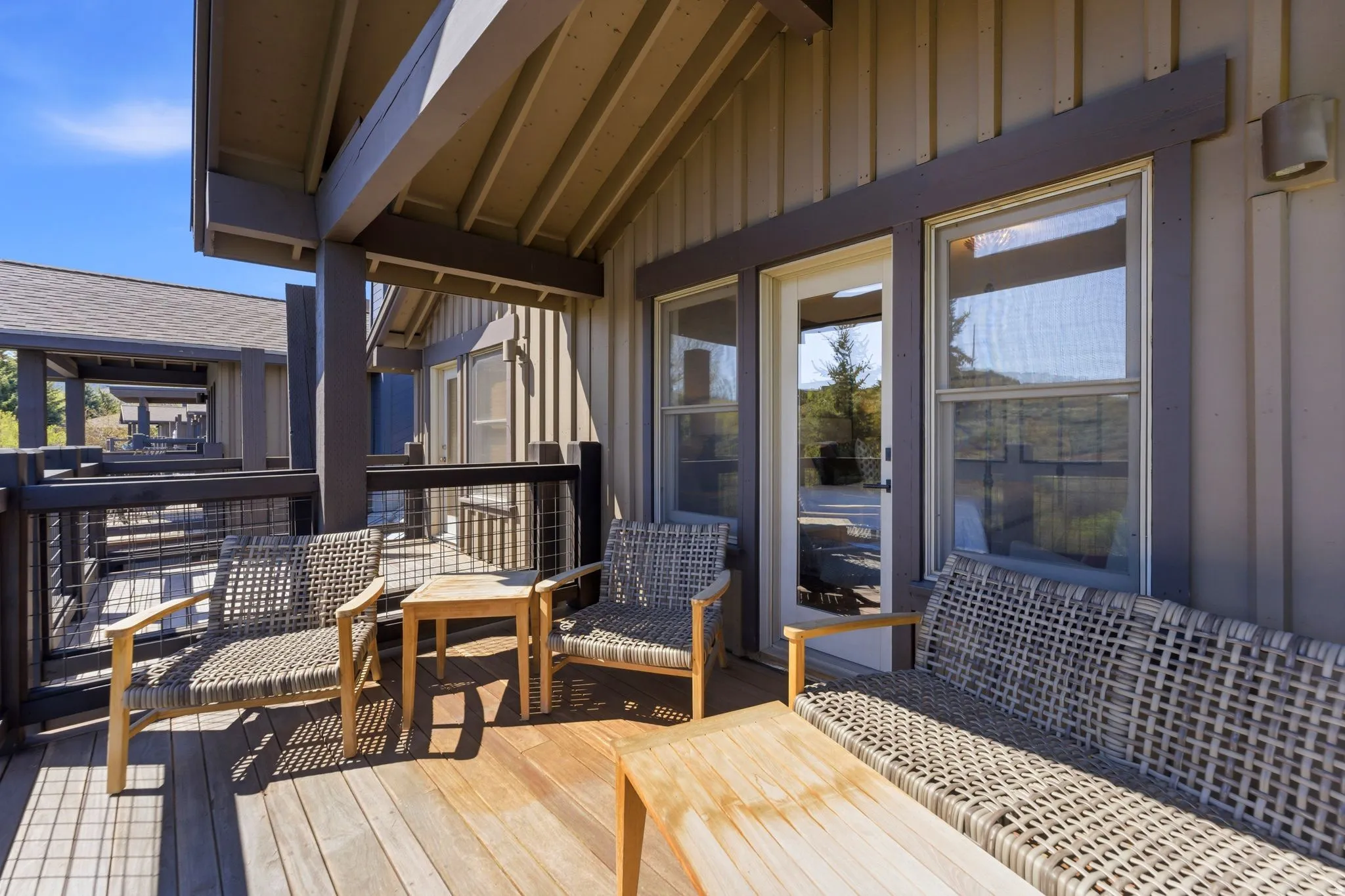 Covered outdoor deck with wood flooring, dark wood railings, and metal mesh infill panels