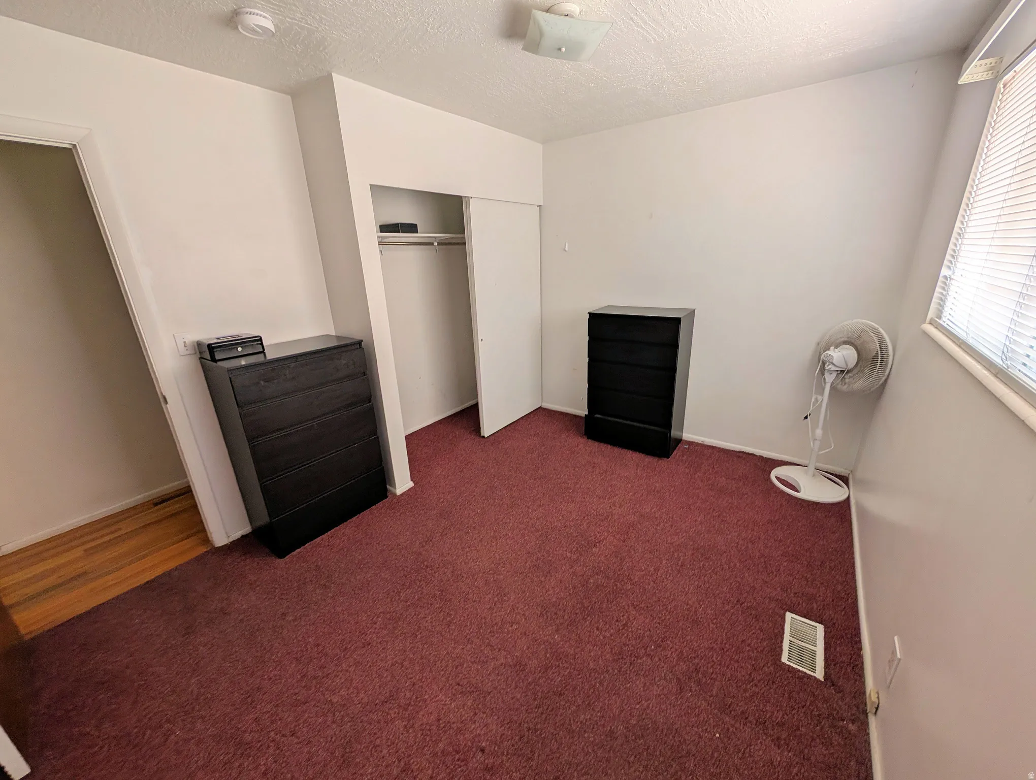Bedroom featuring dark carpet, a textured ceiling, and a closet