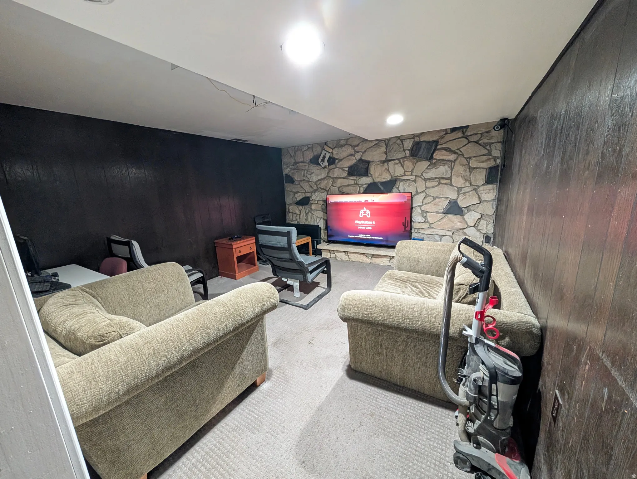 Basement living area featuring carpet floors and wood walls