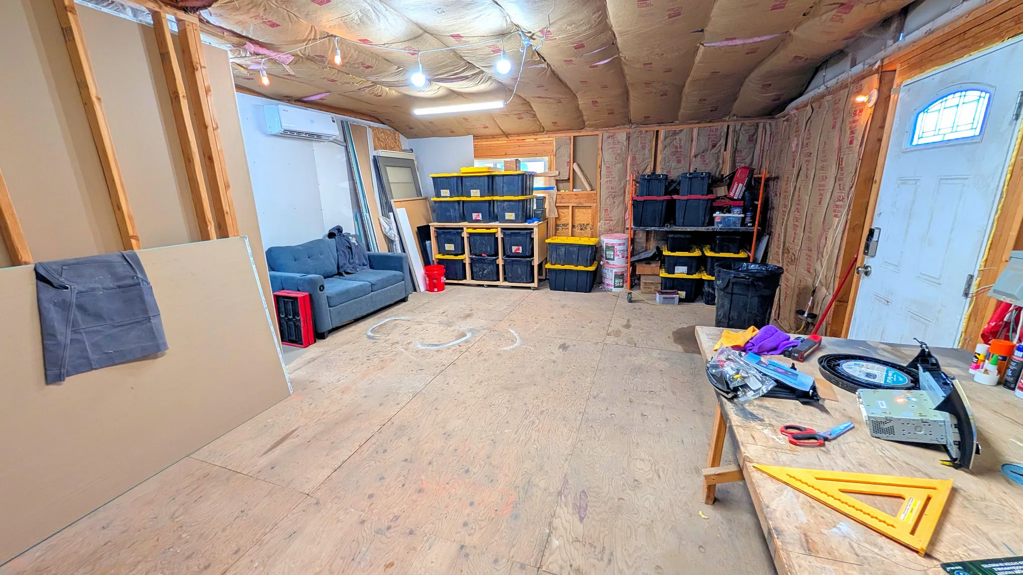 Unfinished interior space featuring exposed wood framing, ceiling insulation, and a plywood subfloor