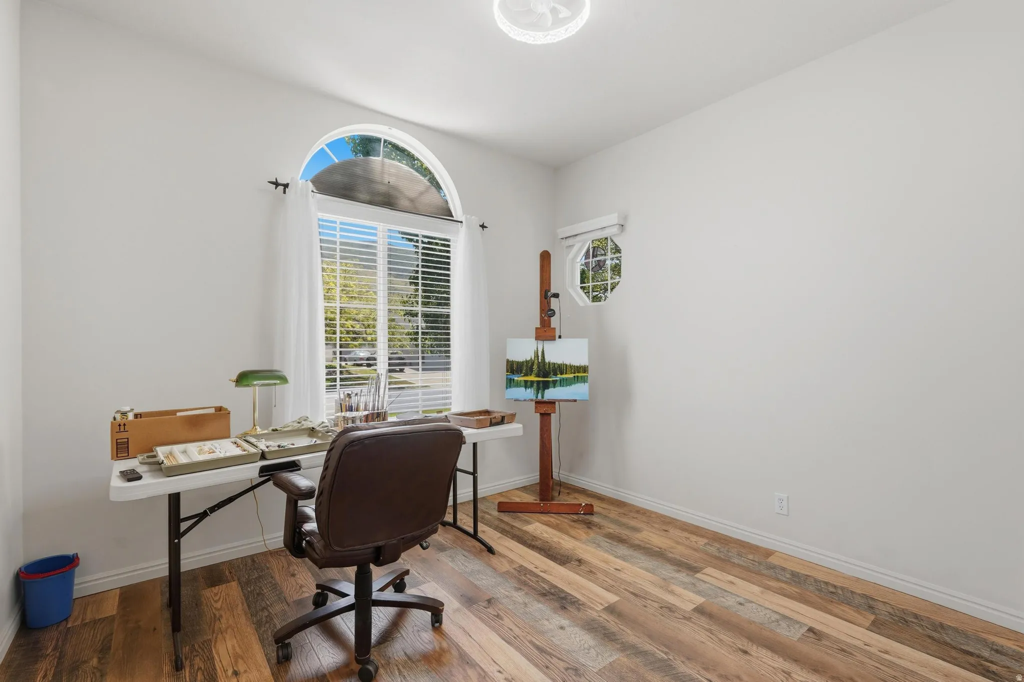 Second bedroom featuring LVP flooring and a prominent arched window with blinds