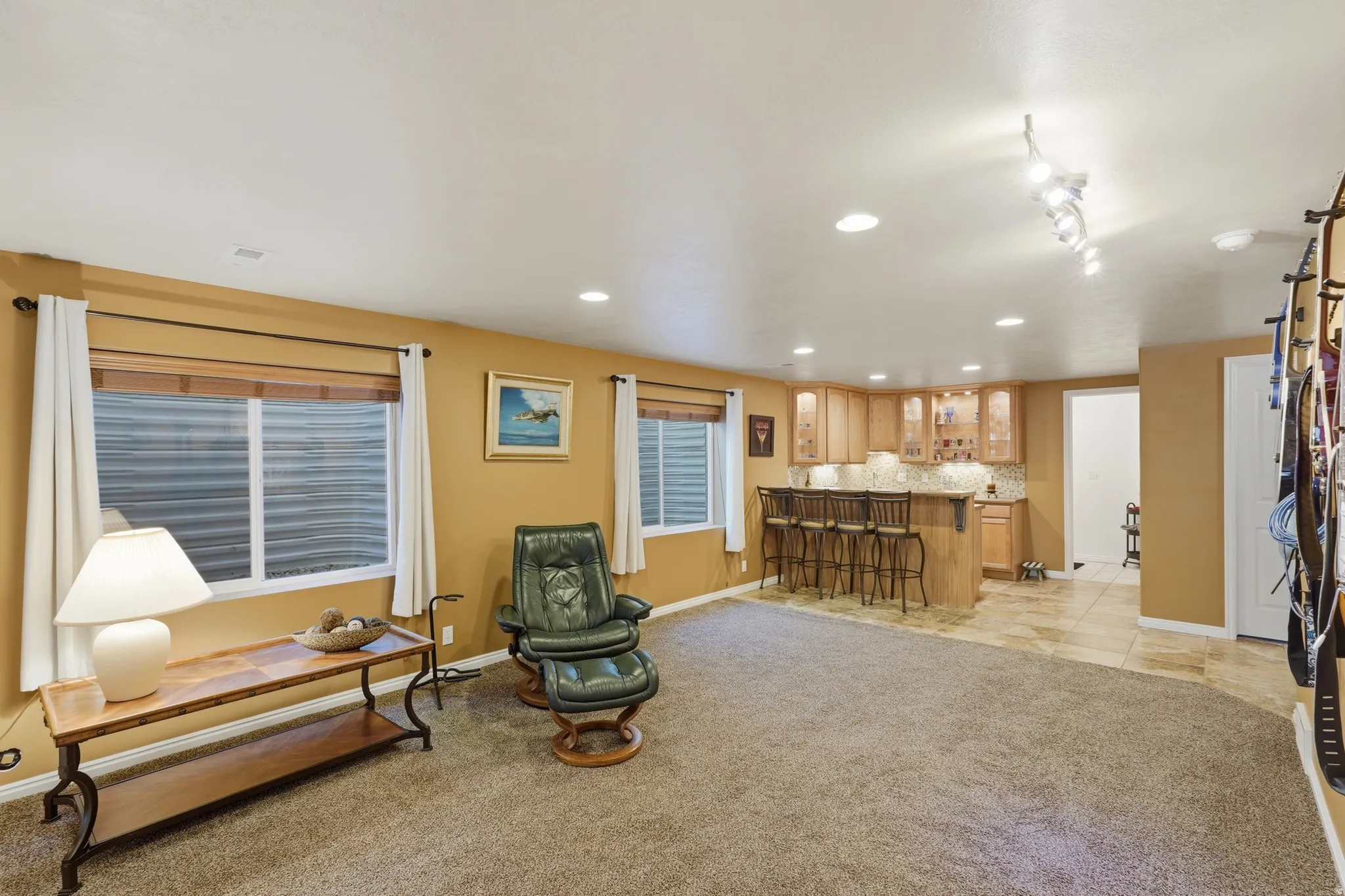 Spacious room featuring recessed lighting a built-in wet bar with wood-finish cabinetry, a stone countertop, and tile flooring