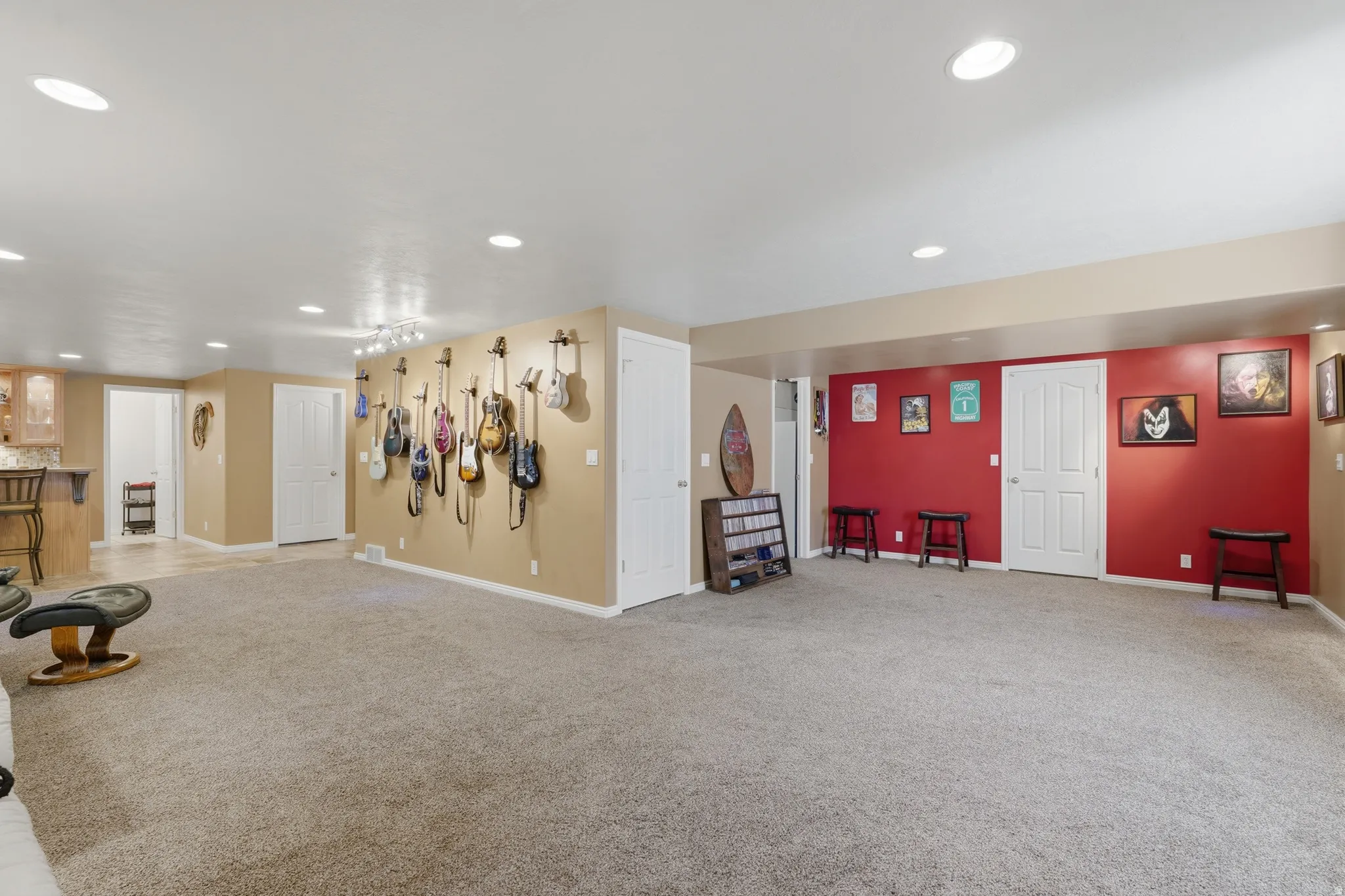 Expansive carpeted room featuring recessed lighting and a built-in wet bar with wood-finish cabinetry and a stone countertop