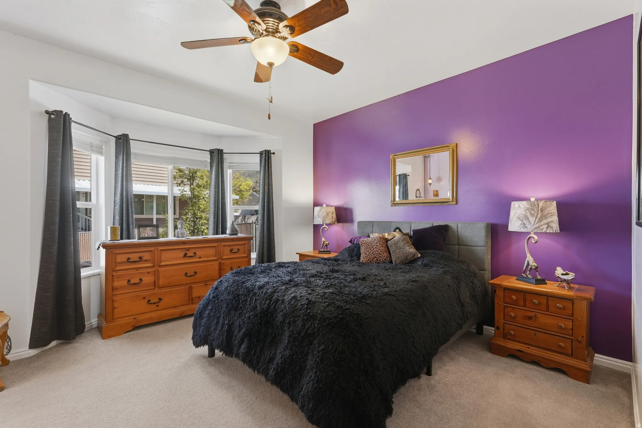 Spacious primary bedroom featuring a bay window and ceiling fan