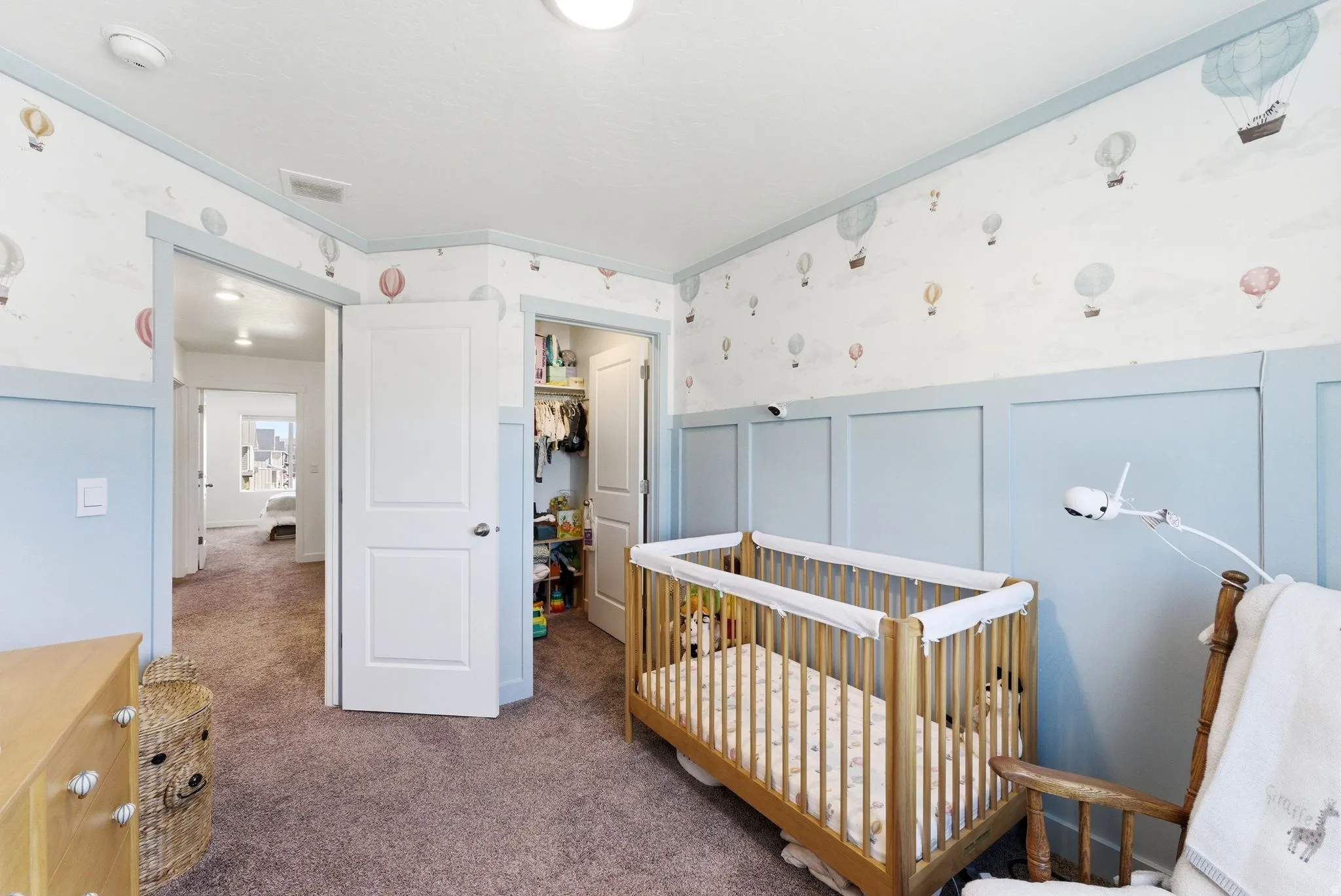 Interior room featuring wall paneling, patterned wallpaper, a built-in closet with double panel door, and plush carpet flooring
