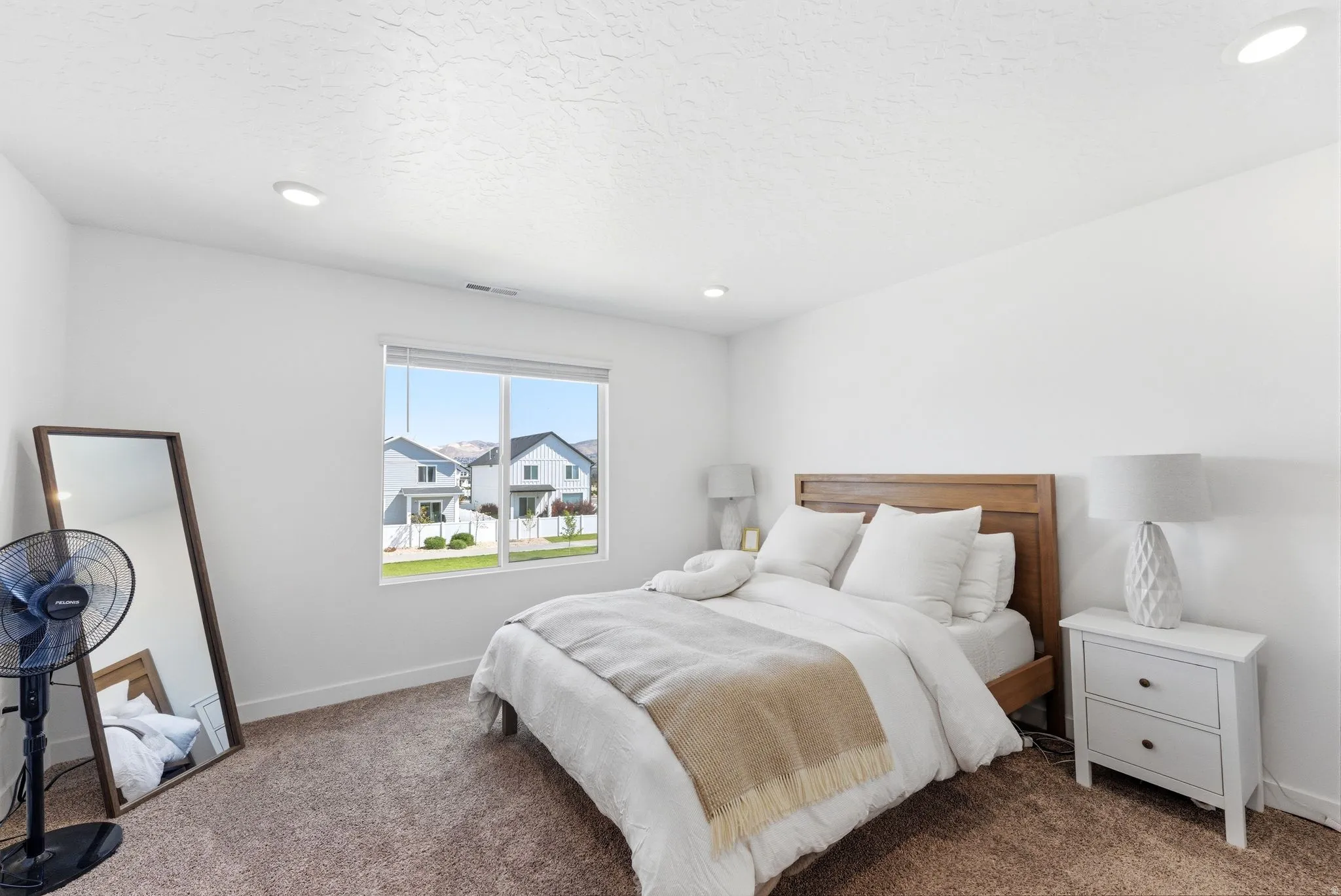 Bedroom featuring a window with natural light, recessed lighting, white walls, and brown carpet flooring