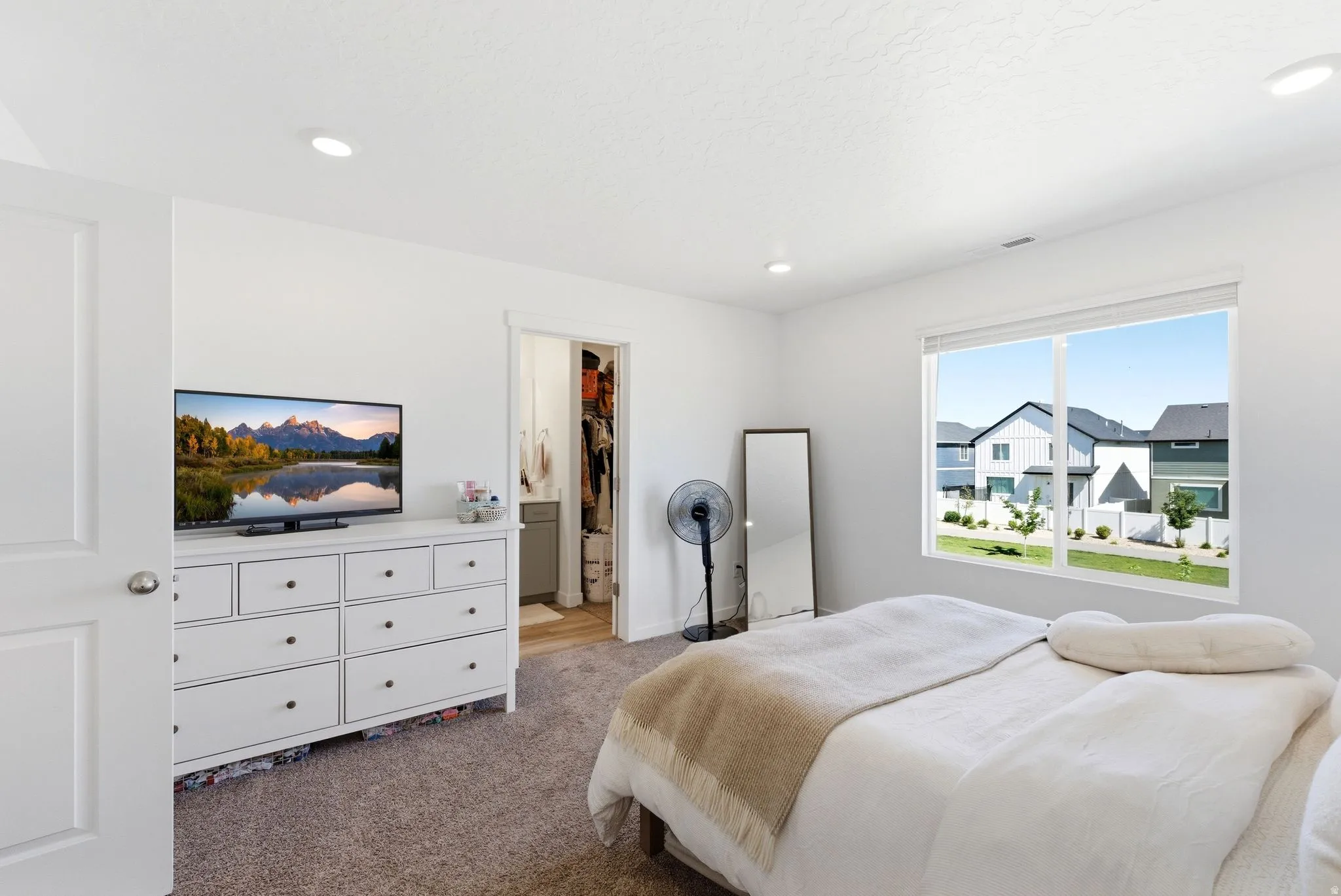 Bright bedroom featuring a large window, recessed lighting, and soft carpet flooring