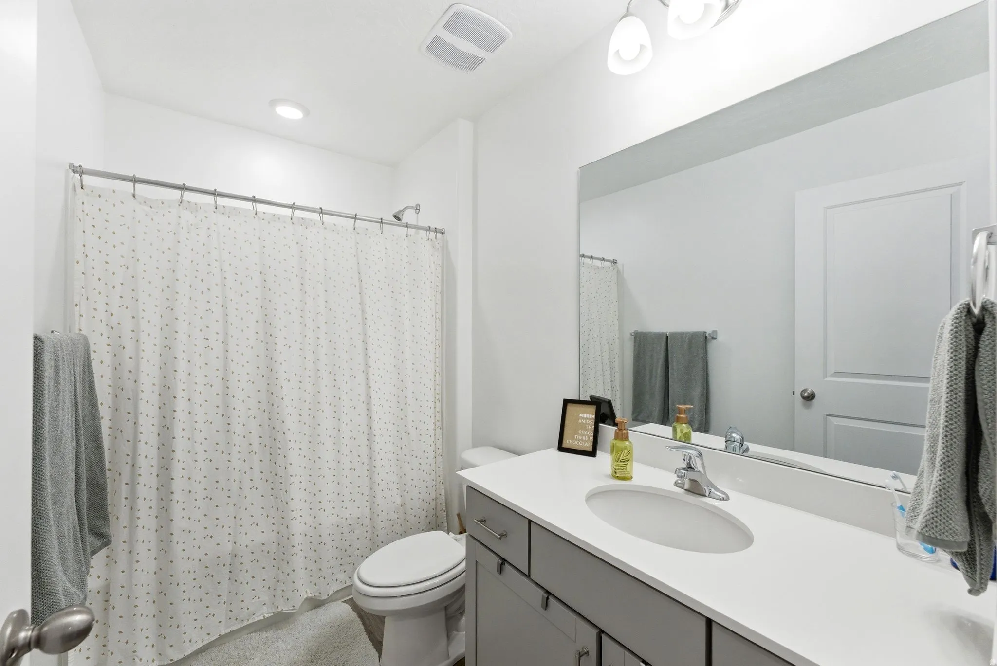 White vanity with integrated sink, chrome faucet, and expansive mirror