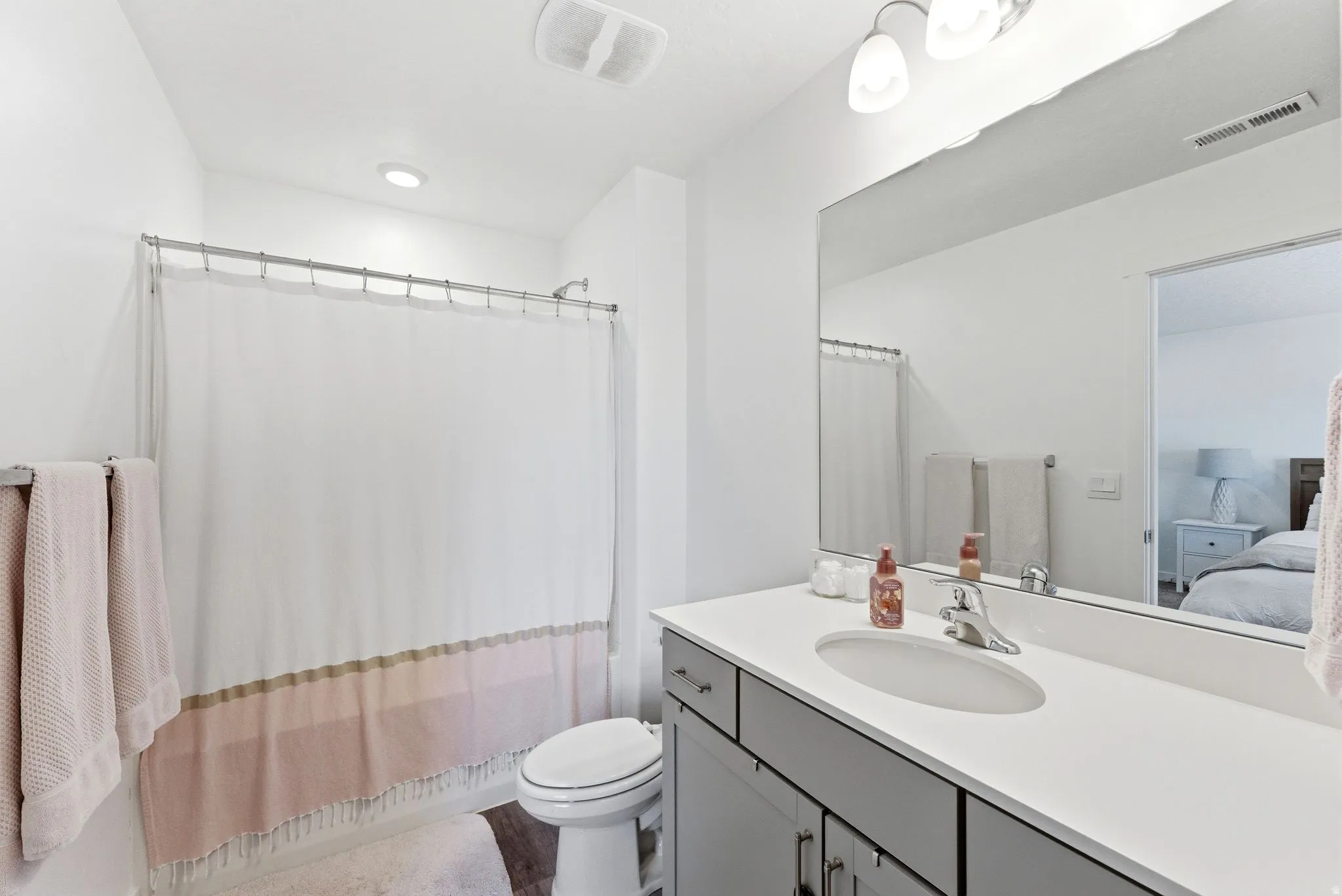 Full bathroom featuring a single vanity with a white countertop, undermount sink, and chrome faucet