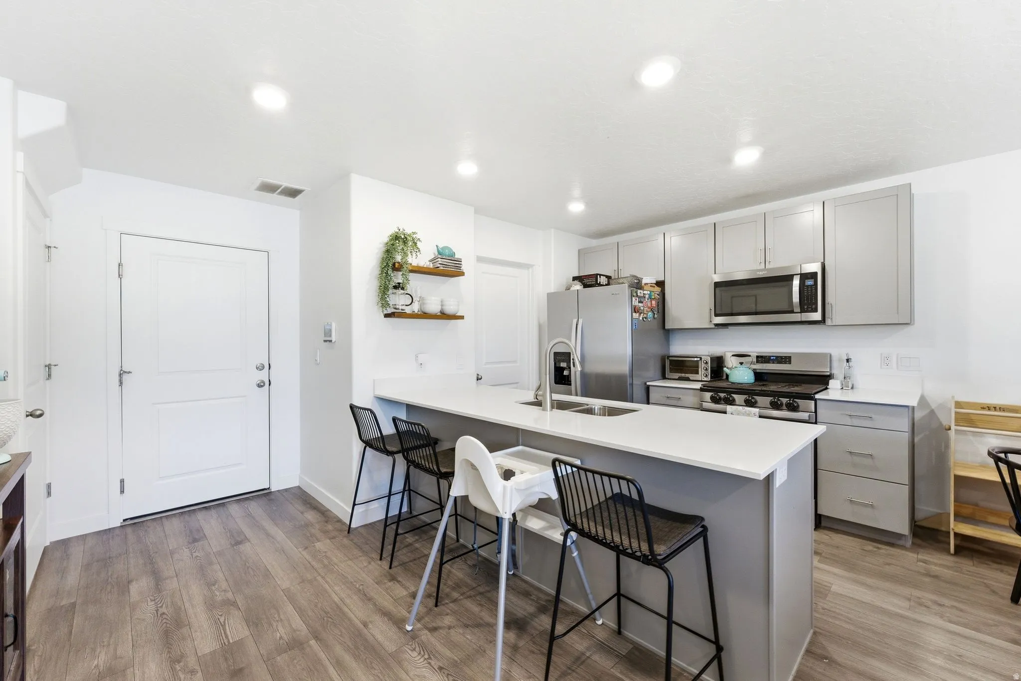 Modern kitchen featuring light gray cabinetry, stainless steel appliances, and a central island with an integrated sink